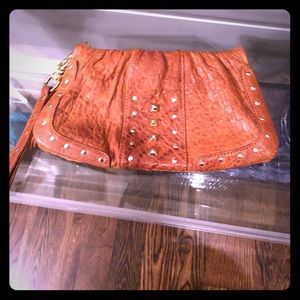Tan wristlet clutch with gold details.